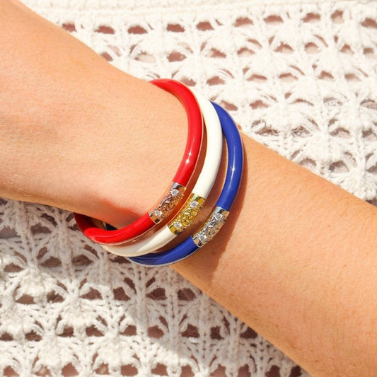 Three colorful bracelets on a wrist with a textured white background