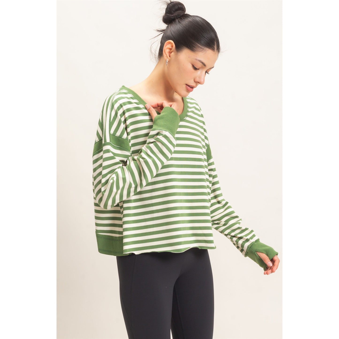 Woman wearing a green and white striped sweater on a plain background