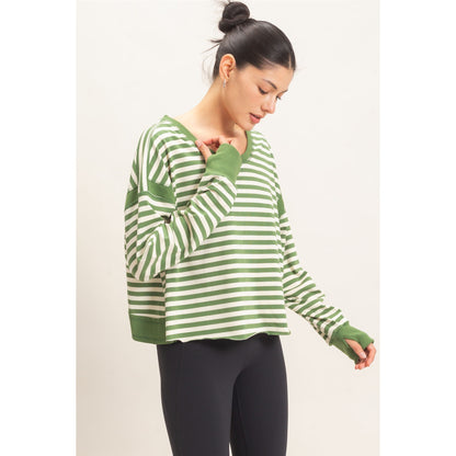 Woman wearing a green and white striped sweater on a plain background