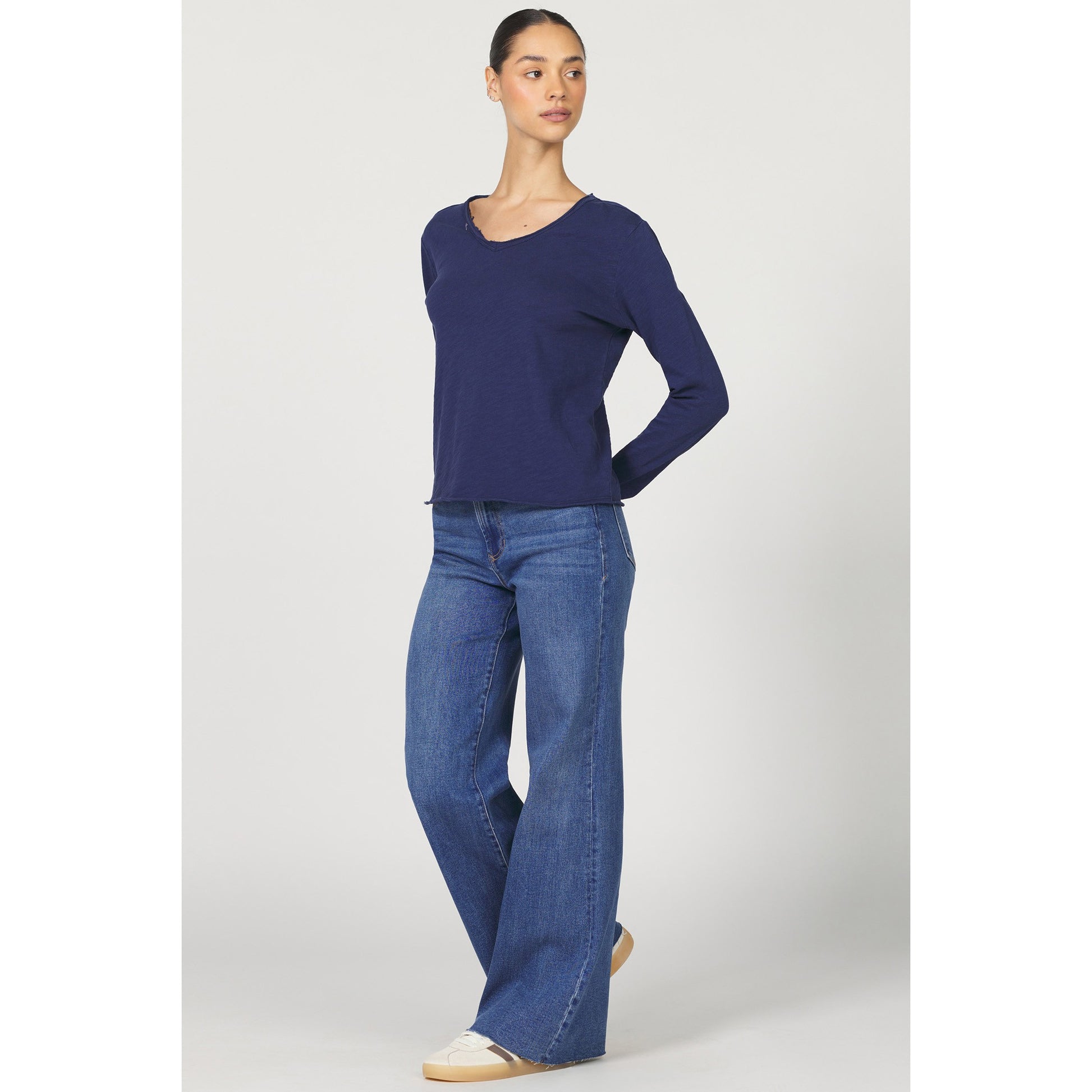 Woman wearing a blue sweater and jeans on a white background