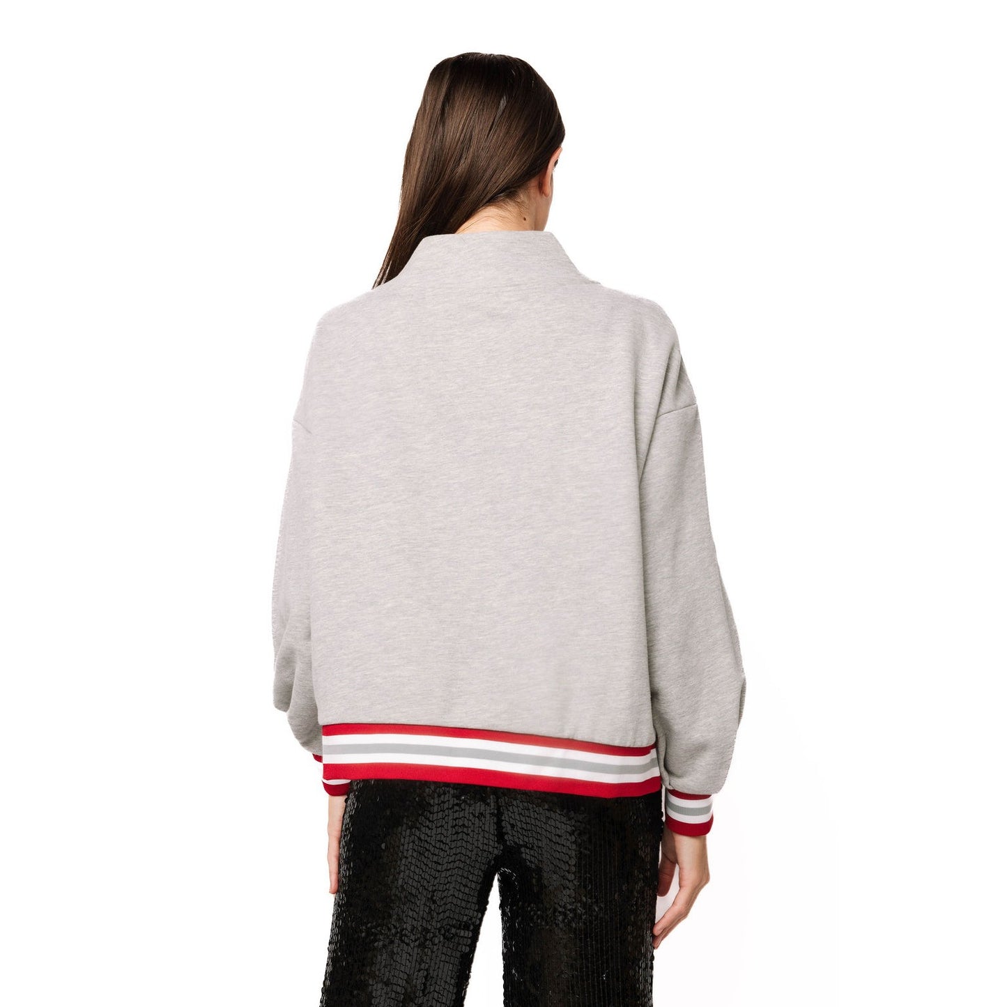 A woman viewed from the back wearing a light gray heathered cropped jacket with red, white, and gray striped ribbed hem and cuffs, paired with black sequined pants, on a solid white background.