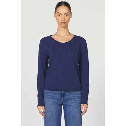 Woman wearing a navy long-sleeve top and blue jeans on a white background