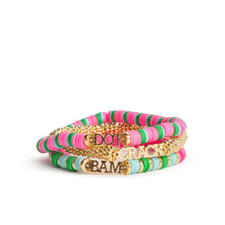 A stack of four beaded bracelets on a white background. The bracelets feature pink, green, and blue striped beads, gold chain links, and gold-tone letter charms spelling 'DOT CRACK BAME'.