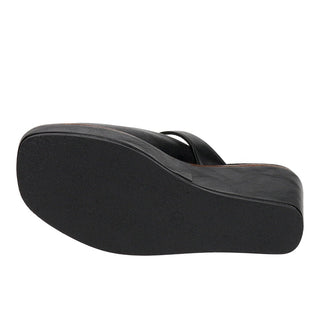 A black wedge sandal shown from a side profile view, highlighting its thick platform sole and single strap, on a solid white background.
