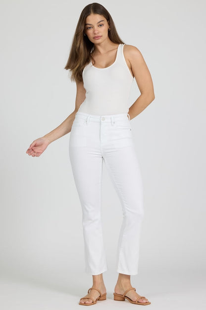 Woman wearing a white sleeveless top and white pants on a plain background