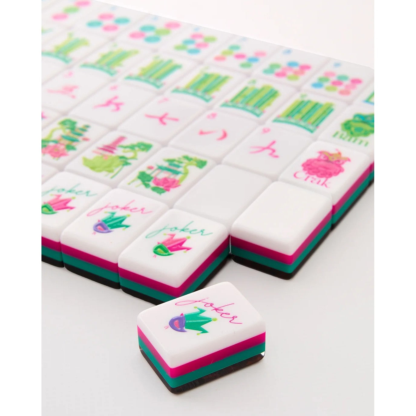 Colorful mahjong tiles with cartoon frog designs on a white background