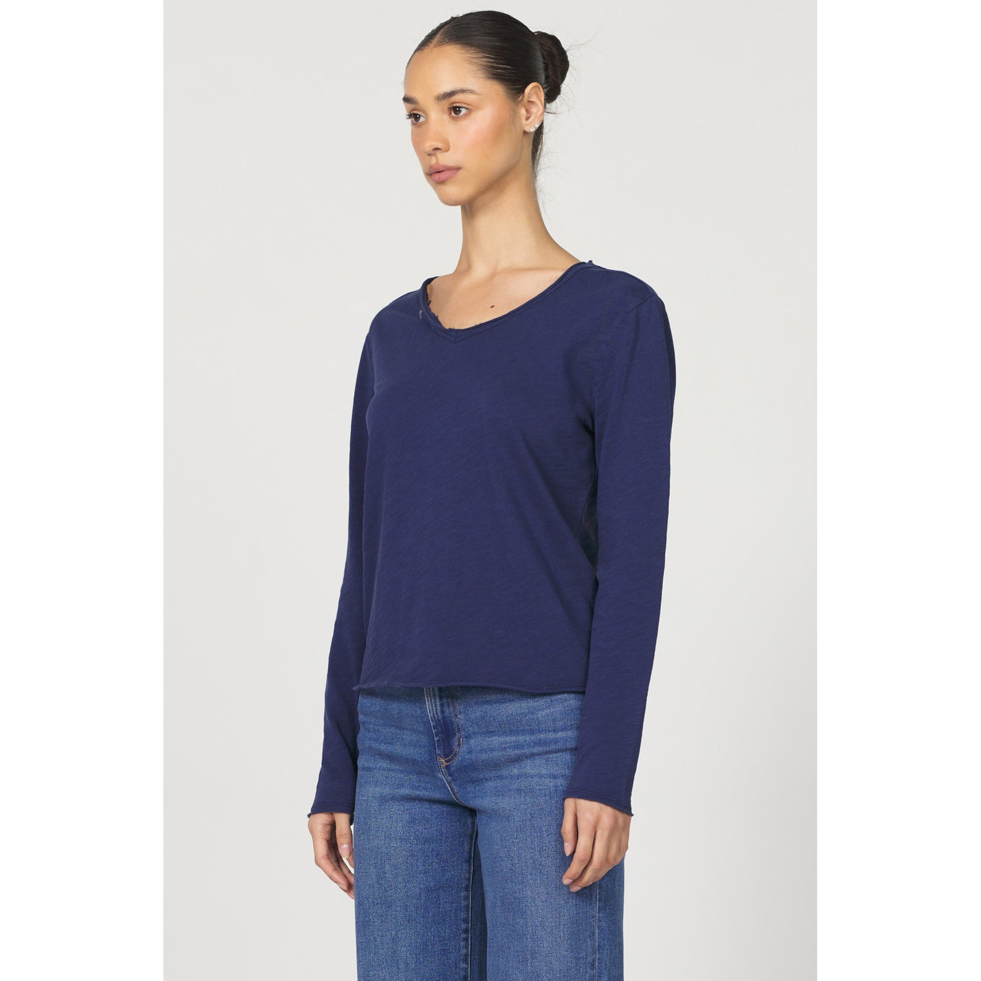 Woman wearing a blue long-sleeve top and jeans on a white background