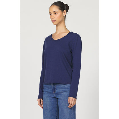 Woman wearing a blue long-sleeve top and jeans on a white background