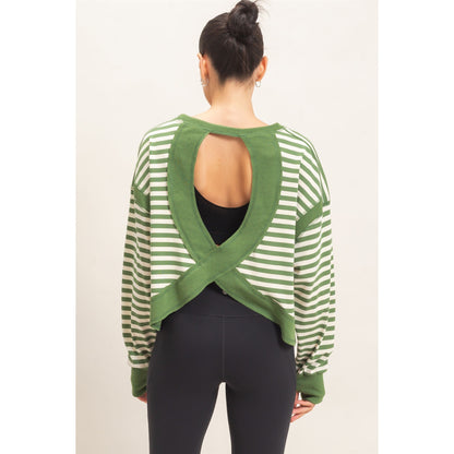 Person wearing a green and white striped sweater with a cut-out back design.