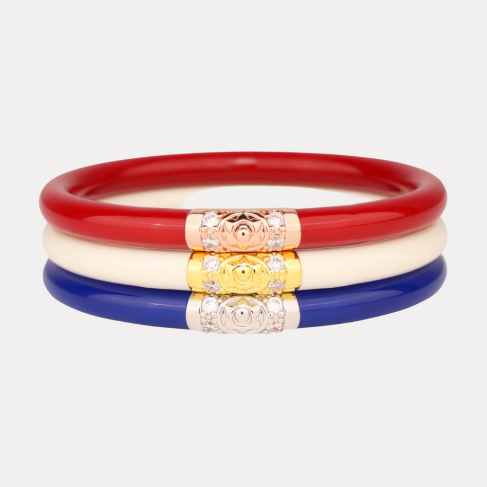 Set of three colorful bangles with decorative ends on a light gray background